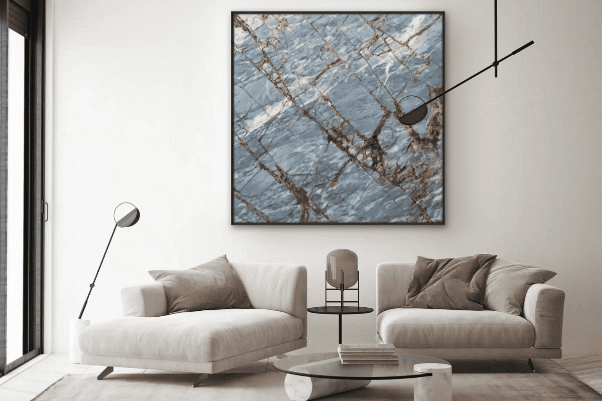 Ein modernes Wohnzimmer mit einem großen Steinbild über dem grauen Sofa.